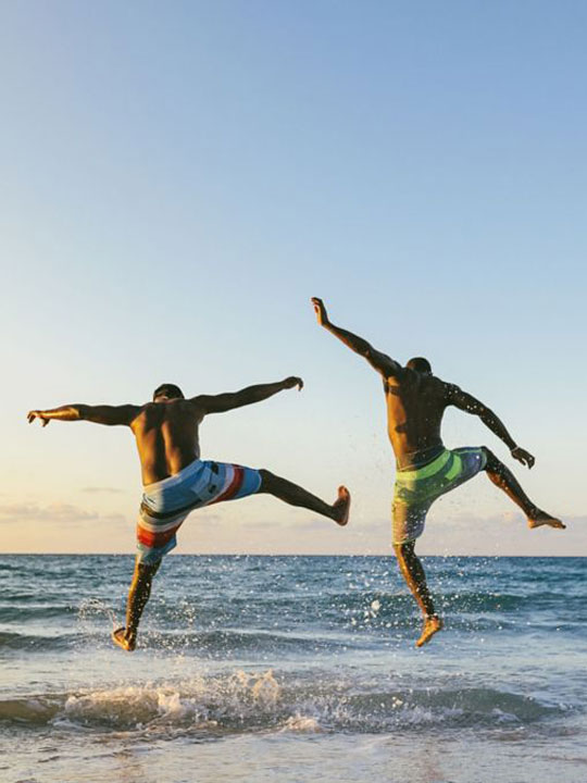 Two adults jumping in the sea.