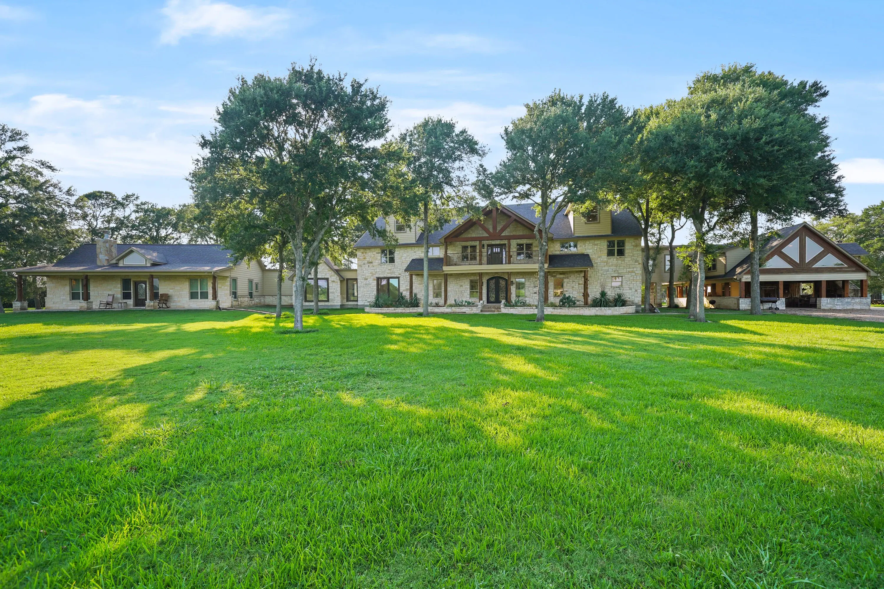 The main home has over 13,000 square feet of living and entertaining space, including thirteen bedrooms, four kitchens, and custom finishes and craftsmanship. With stunning high ceilings covered in wood, eye-catching light fixtures, and warm stone details