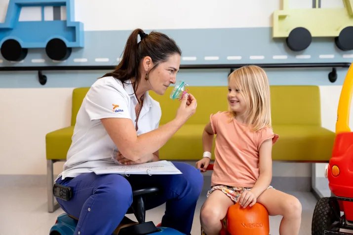 Pedagogisch medewerker legt aan een kindje uit het dagziekenhuis kinderziekten campus Rumbeke uit hoe een anesthesiemasker werkt. 