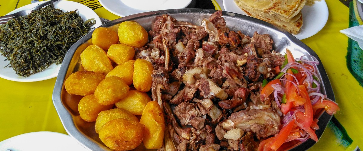 Platter of a traditional East Africa cuisine, Nyama choma and accompaniments of kachumbari salad, sukuma wiki, chapati and roast potatoes
