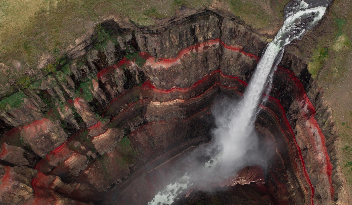 Aerial view of Hengifoss waterfall and red and green erosion rocks in Iceland