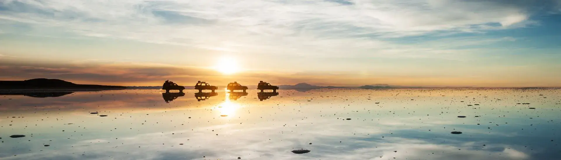 Panoramic sunset with caravan over the Uyuni Salt Flats