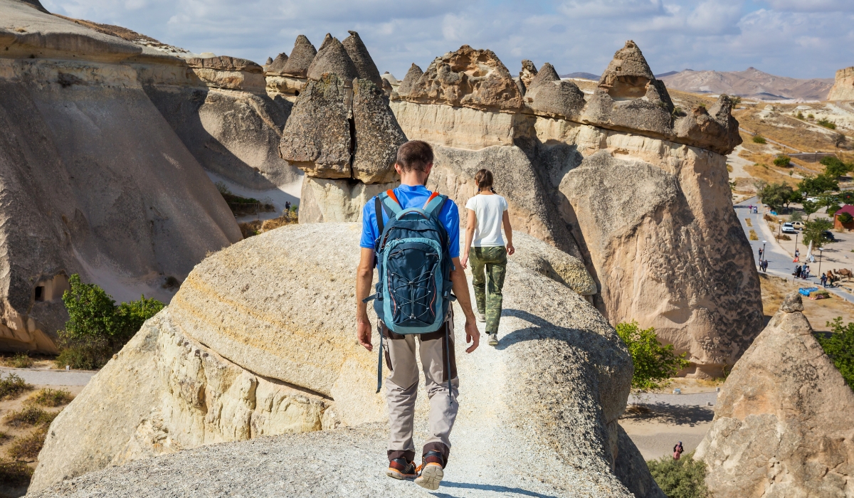 Travelers exploring and hiking hoodoo fairy chimney rock formations in Cappadocia, Turkey
