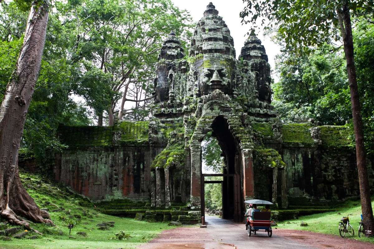 Tuk tuk entering archway of Angkor Wat temple in Siem Reap Cambodia