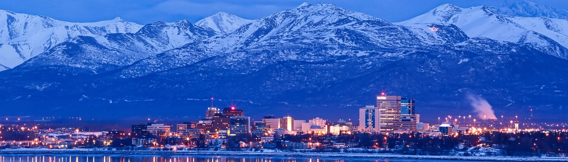 Snow-capped mountains and buildings at night in Anchorage, Alaska