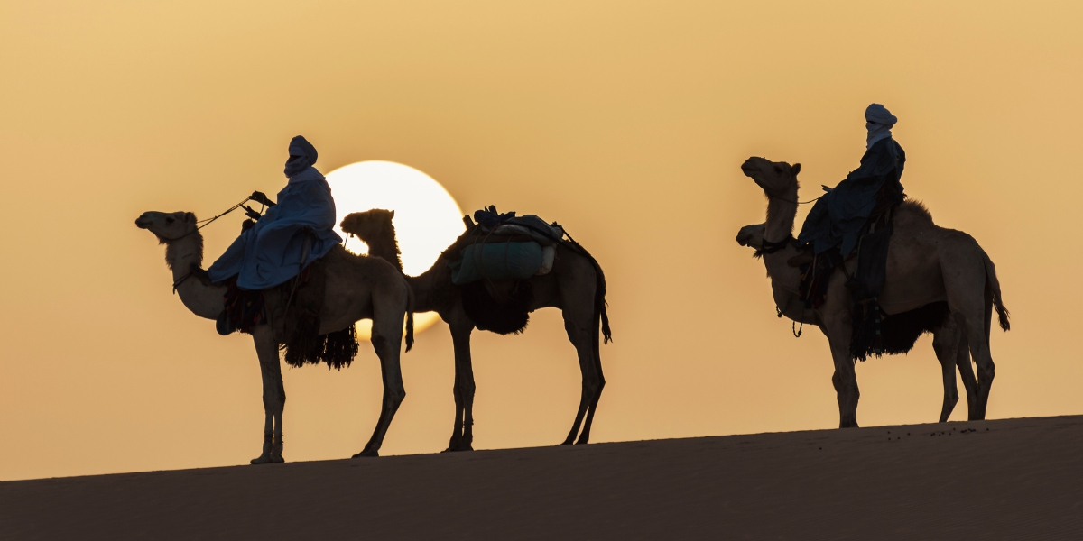 Two people riding camels in the desert