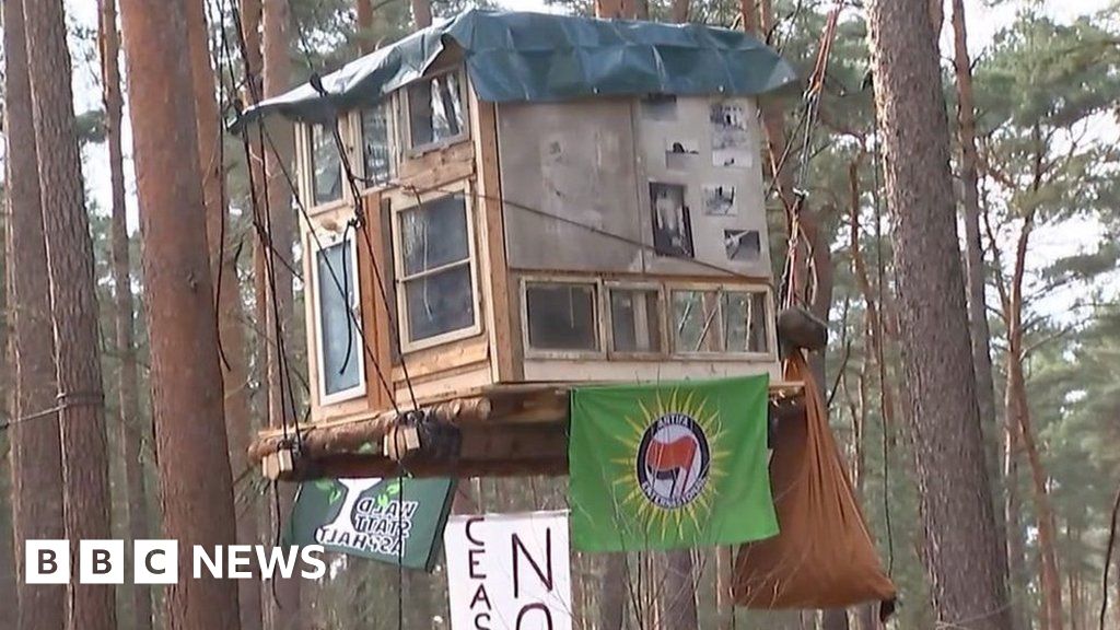 Tesla electric car factory expansion plan sparks treetop protest near Berlin, Germany.