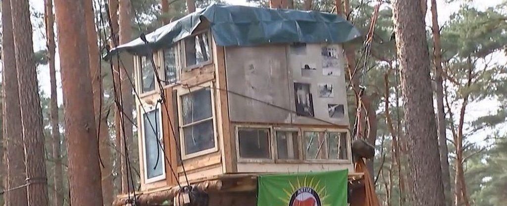 Tesla electric car factory expansion plan sparks treetop protest near Berlin, Germany.