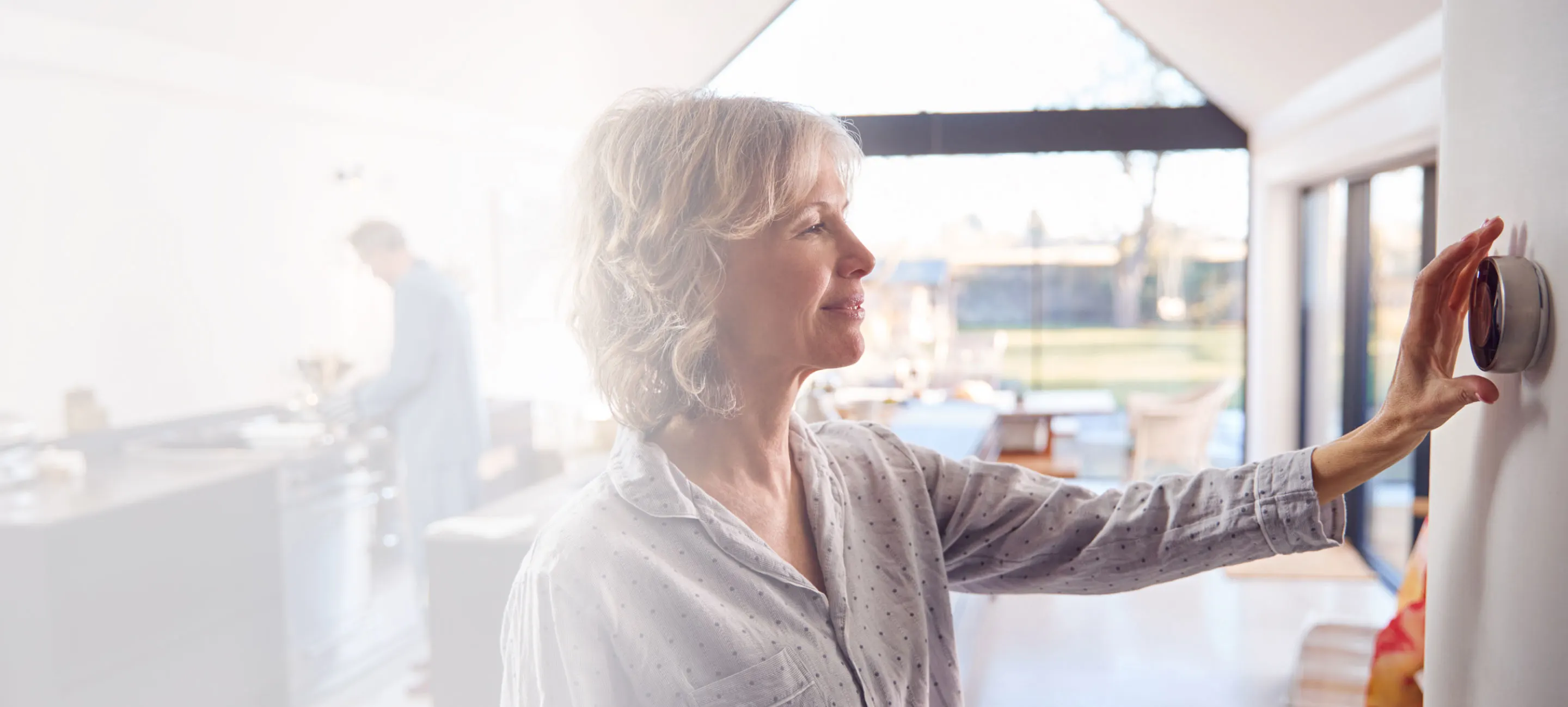 woman adjusting a smart thermostat