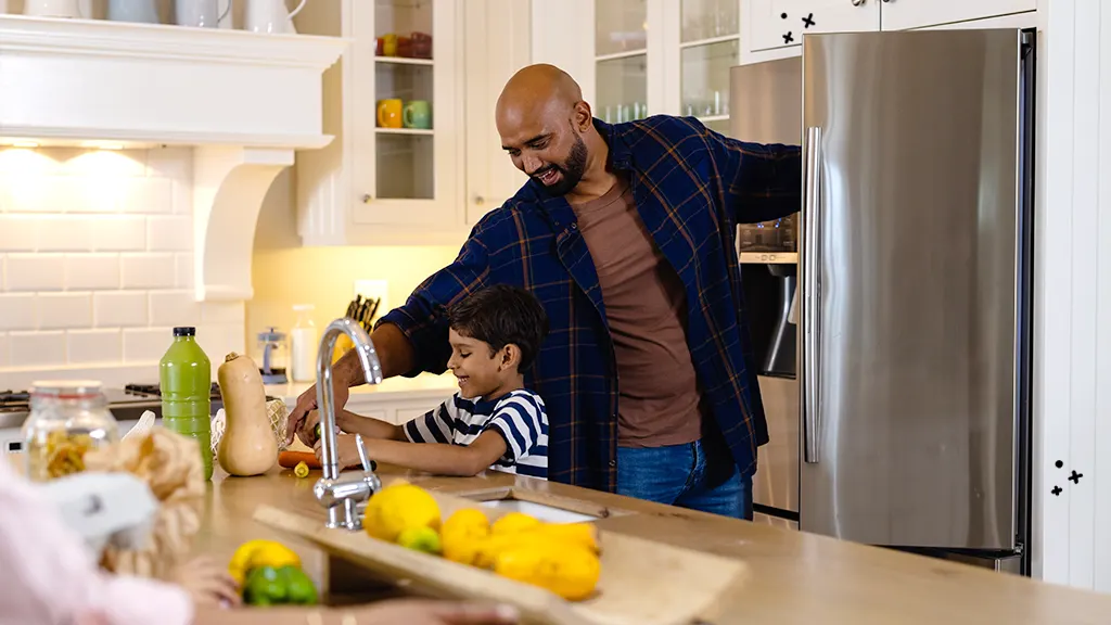 Father and son unloading groceries into their refrigerator