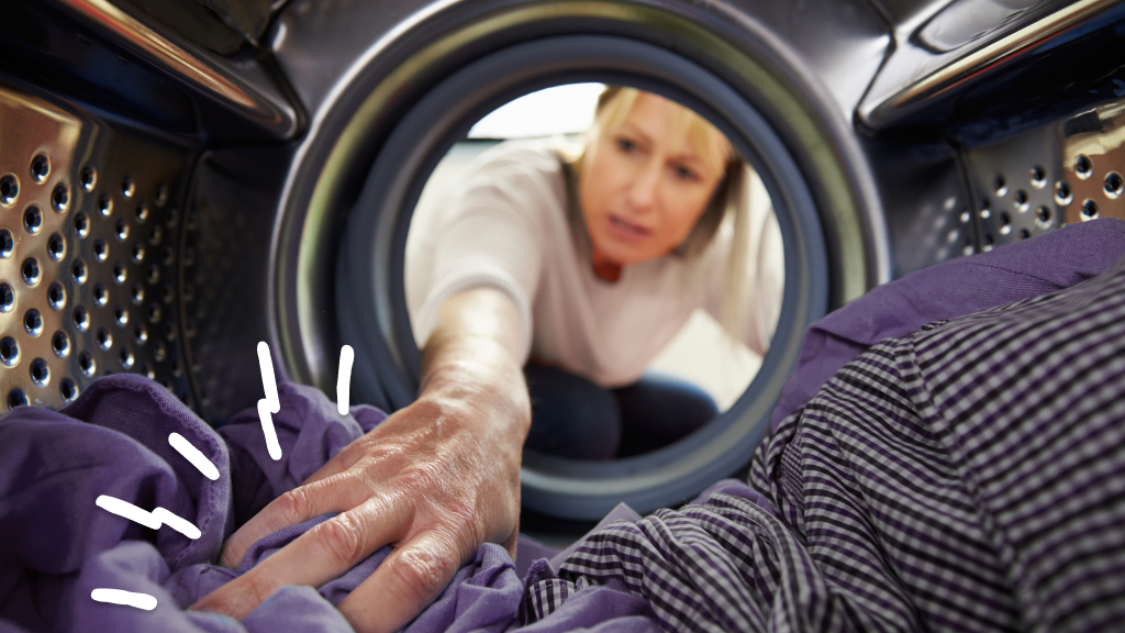 Woman reaching into dryer to feel clothes