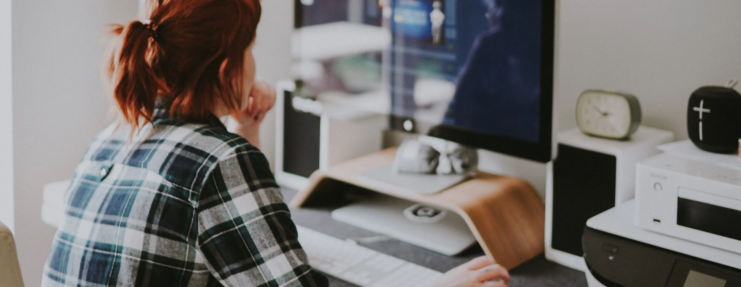 Person working at desk with computer, printer, smart speaker