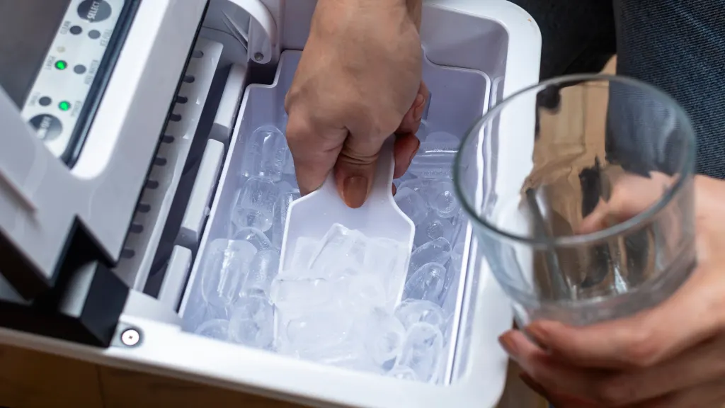 Close-up of a hand holding a scoop, scooping ice from an icemaker