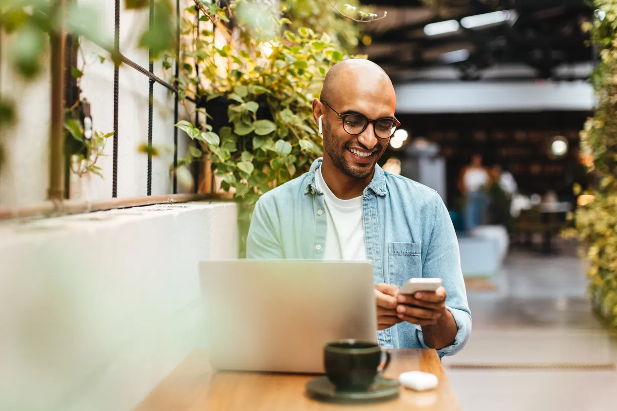 Man using a smartphone to play music in a cafe stock photo