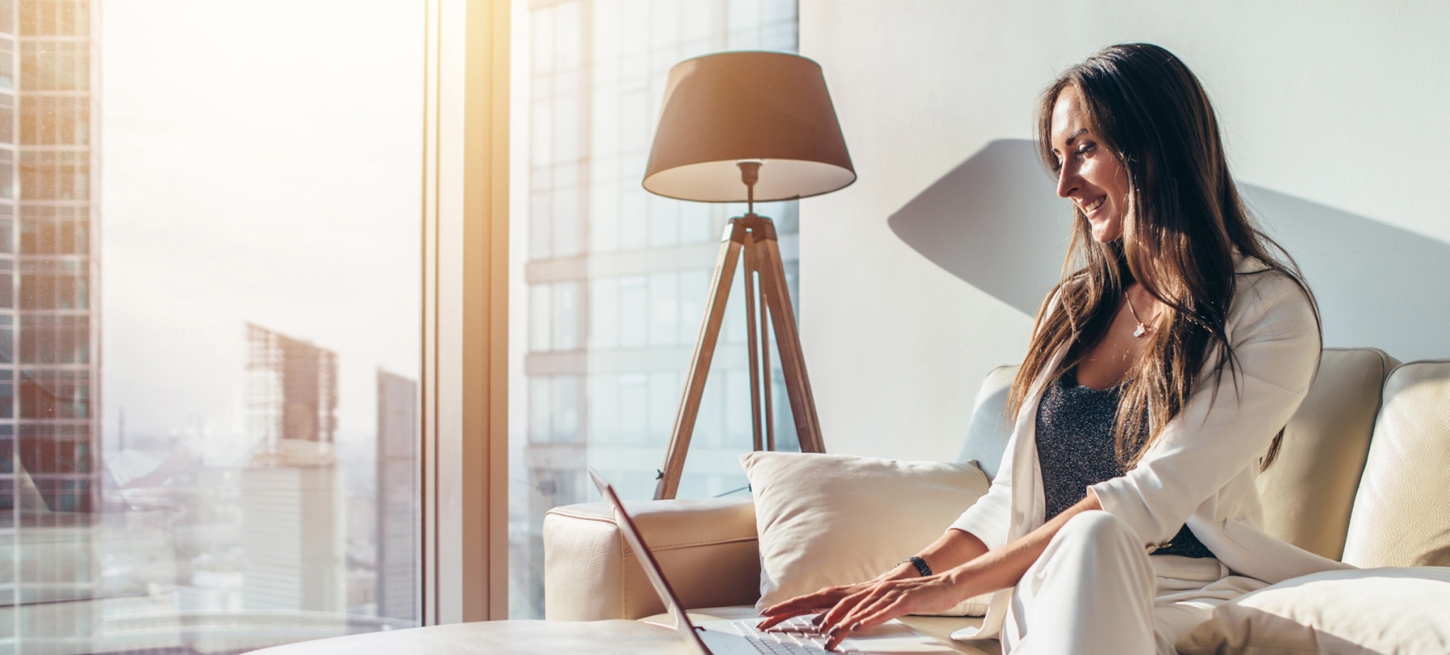 woman sitting in couch and typing on laptop keyboard