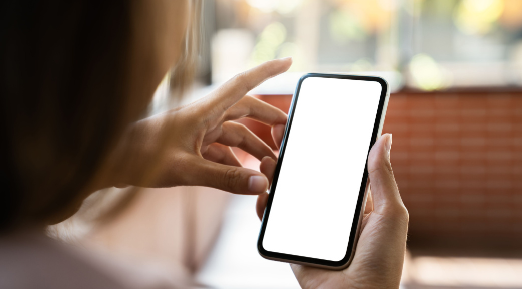 A person holding a phone that is showing a blank screen.