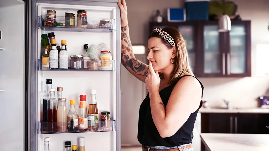 Woman looking inside fridge that's been running longer than normal