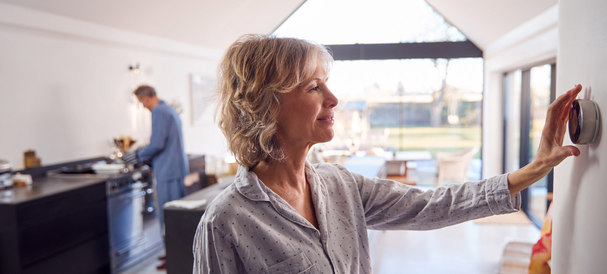 woman adjusting a smart thermostat