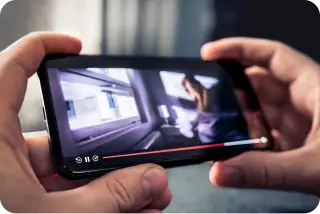 Person holding a smartphone while streaming a video.