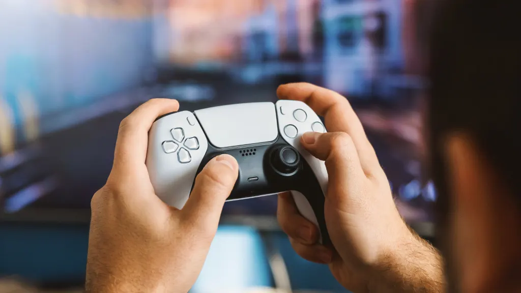 Close up of hands holding a white and black Playstation 5 controller