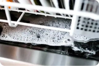 Foam and water inside a dishwasher during a wash cycle.