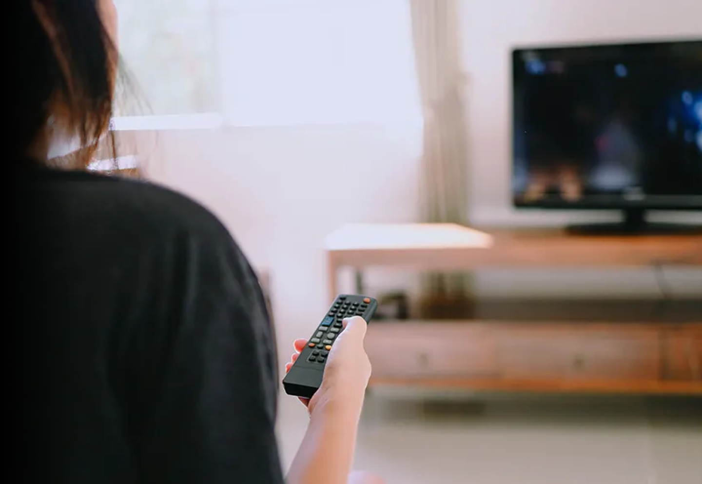 Woman pointing the remote control at her television