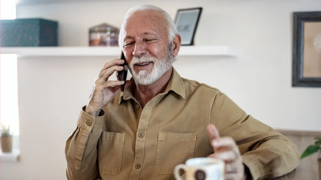 Older gentleman with beard smiling amiably on a phone call