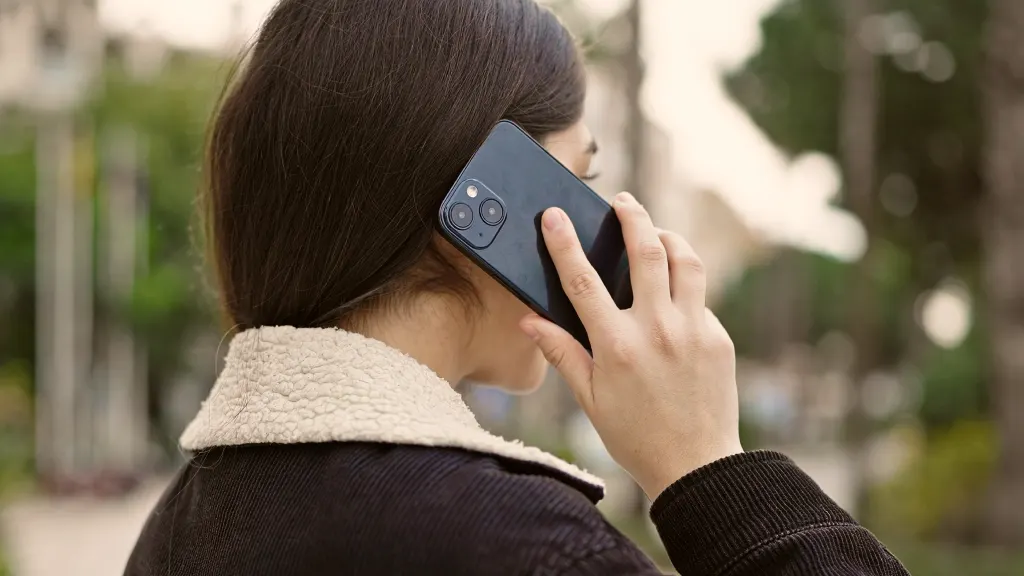 Over-the-shoulder view of a brunette woman holding a black phone to her ear