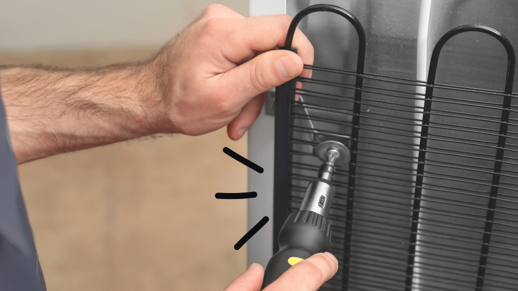 Person cleaning refrigerator coils