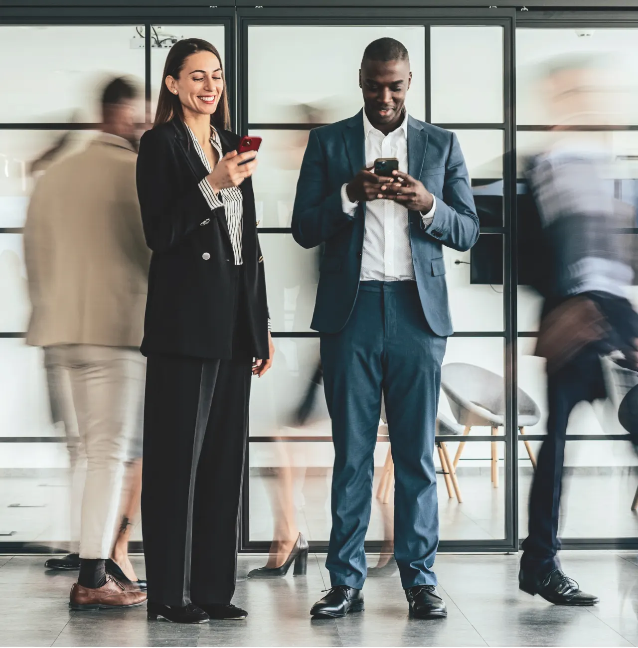 Man and woman using their phones in a busy area