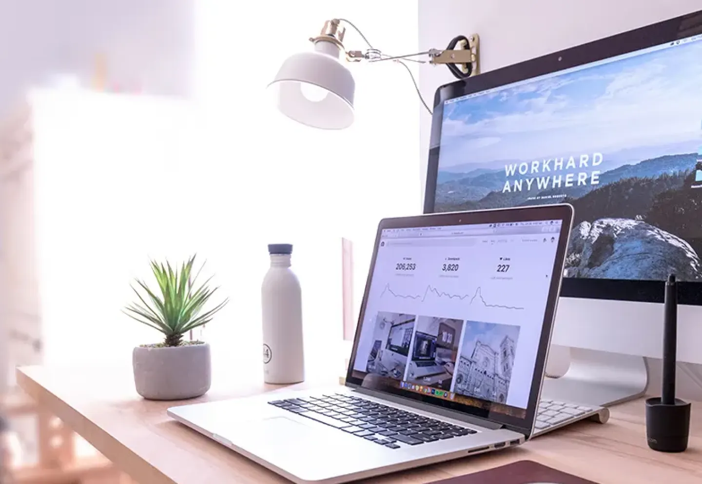 A laptop on a desk with an external monitor displayed behind it
