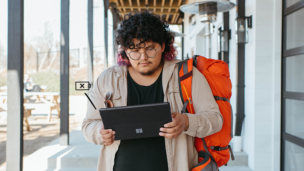 Young person outside walking with backpack and holding a Surface Pro that's not charging