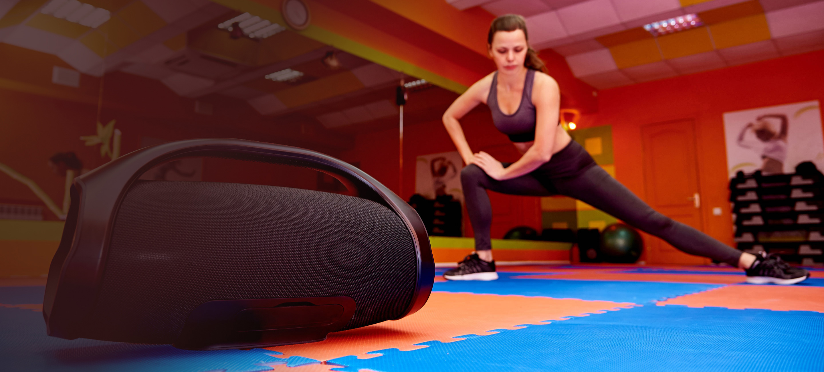 woman doing exercise, a Bluetooth speaker on the floor