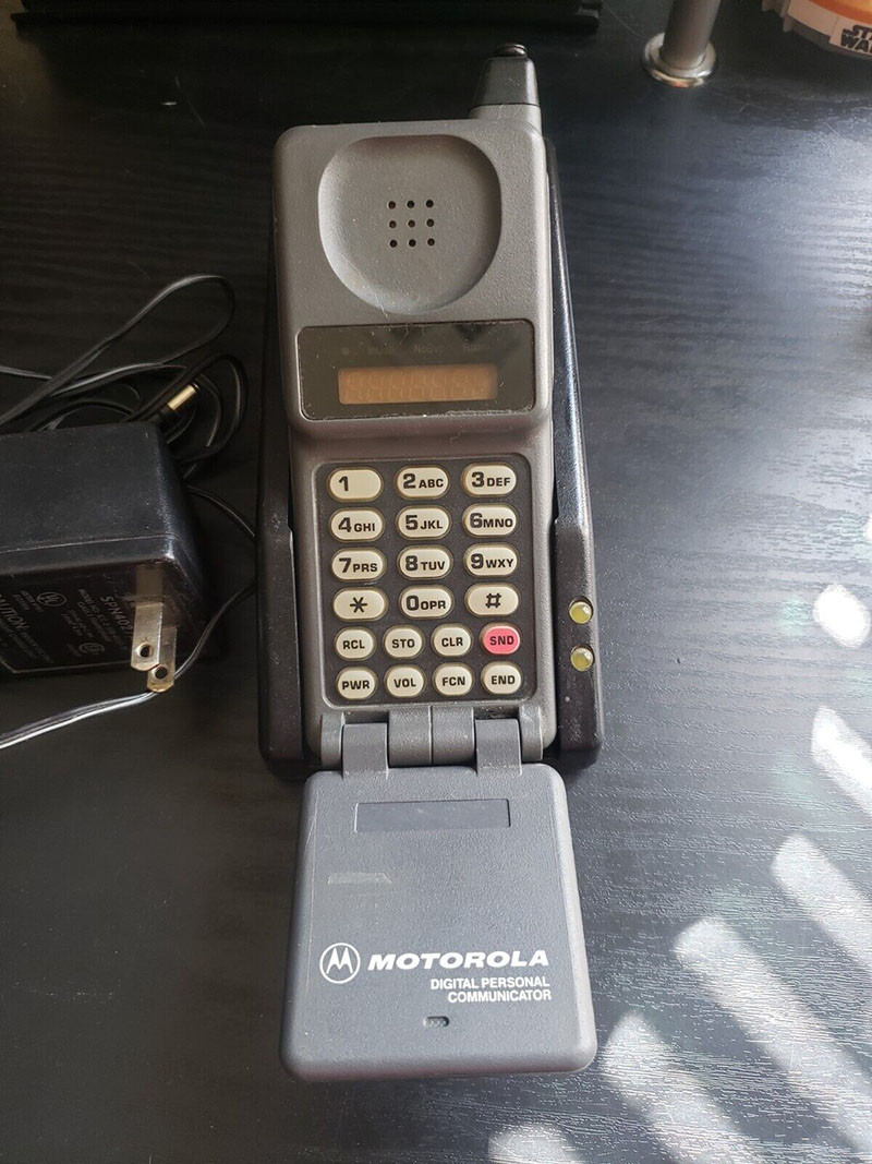A vintage Motorola 90s flip phone with its original charger.