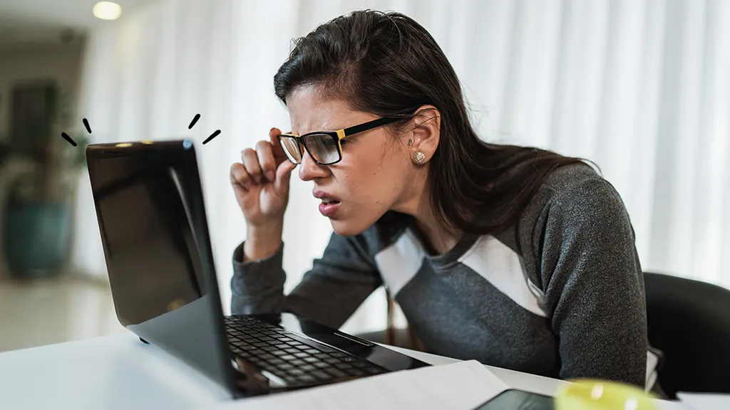 A woman strains as she looks at her laptop screen