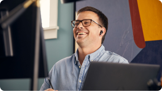 Man laughing while sitting behind a desk with monitors