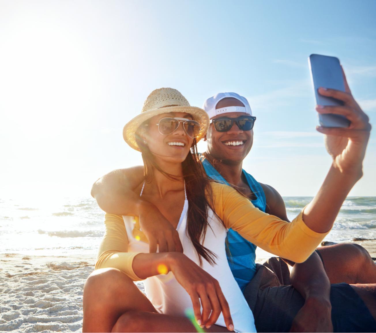 A couple sitting by the ocean looking at their photos on their phone