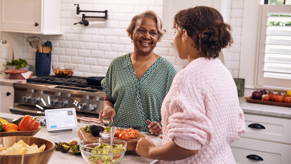 Two people in a kitchen with a smart hub on the counter