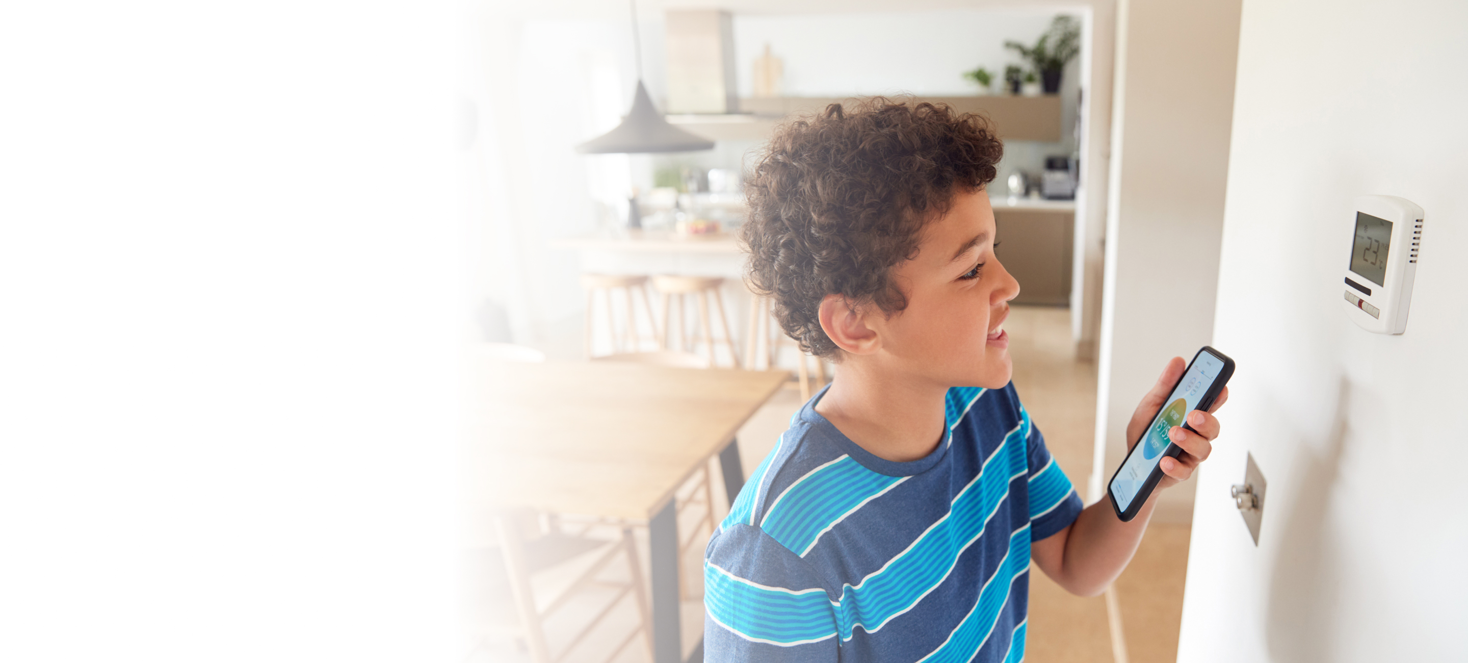 Boy using smartphone with thermostat