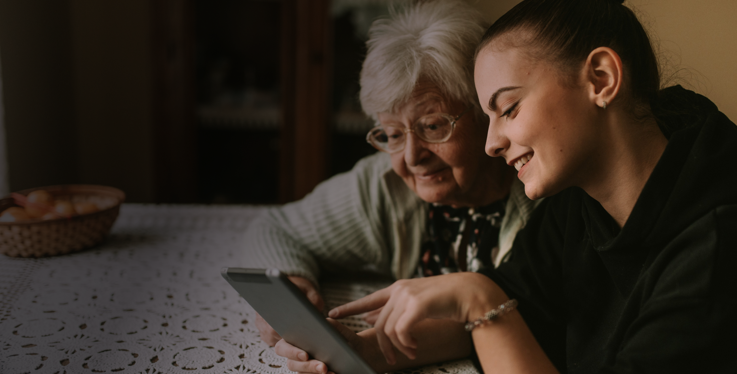 A grandmother and grand daughter looking a tablet screen 