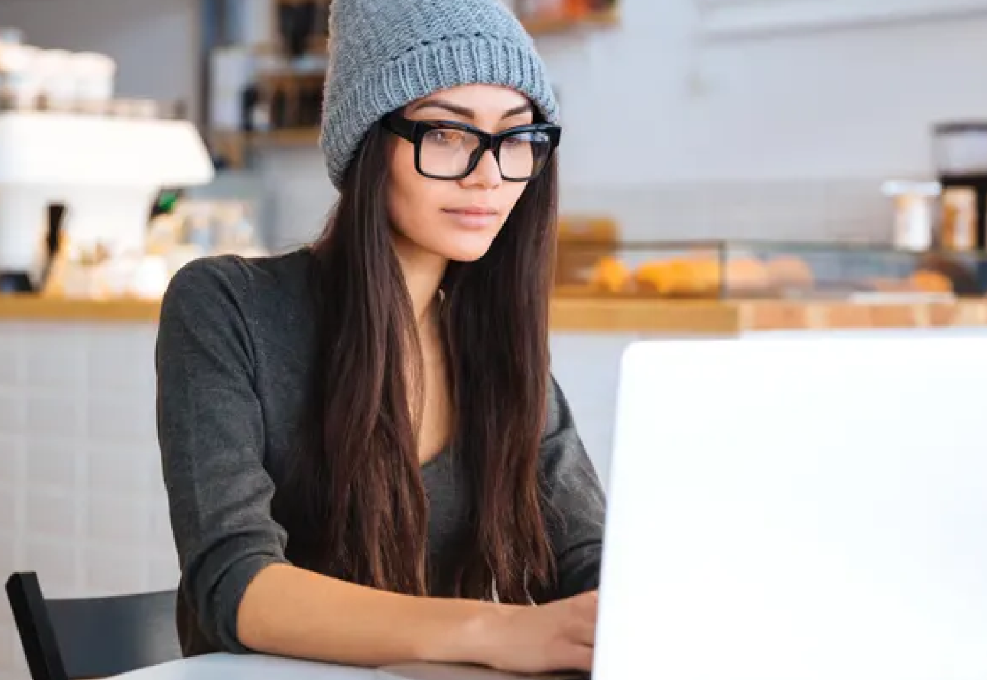 A woman sitting in a coffee shop working on her laptop