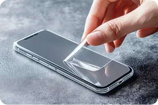Person placing a screen protector on a phone lying on a table