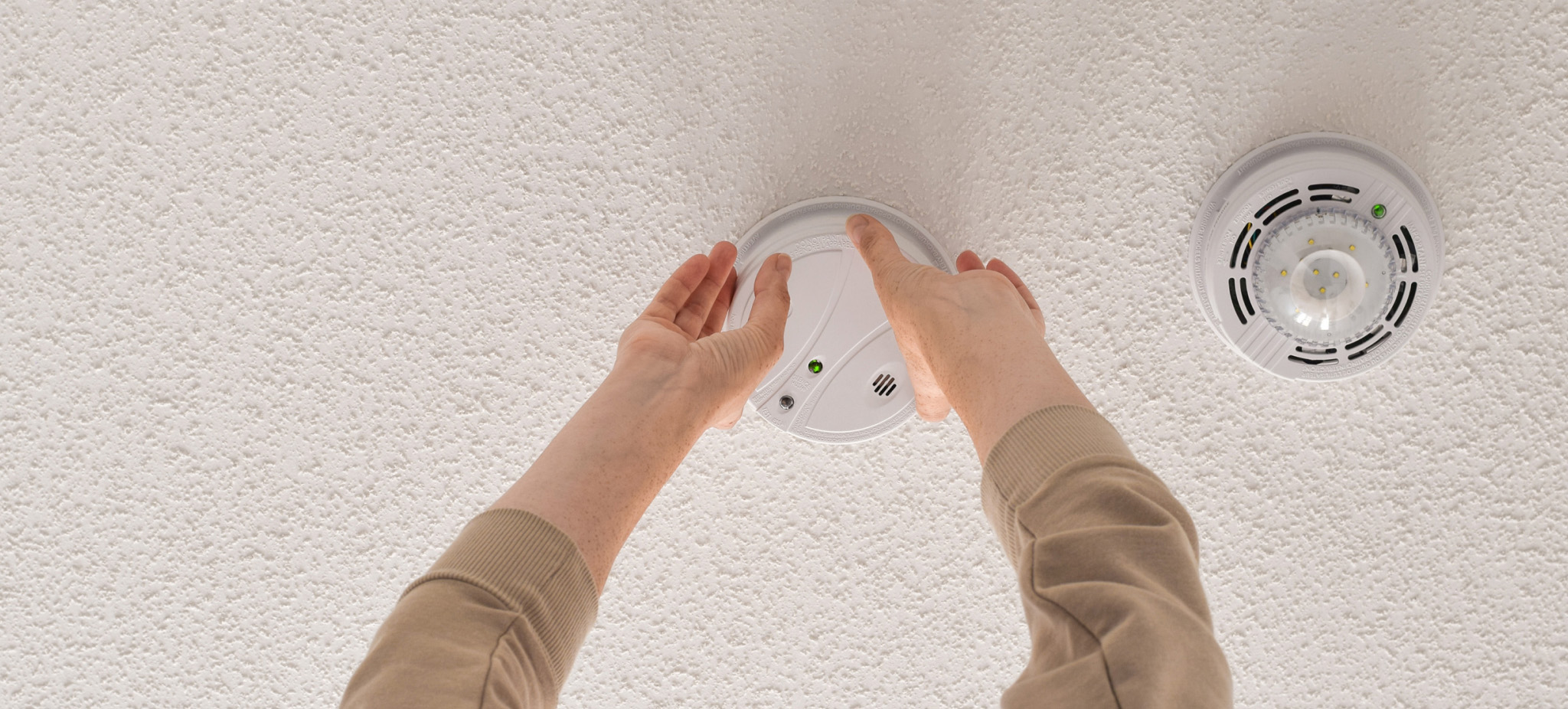 Man checking smart smoke alarm