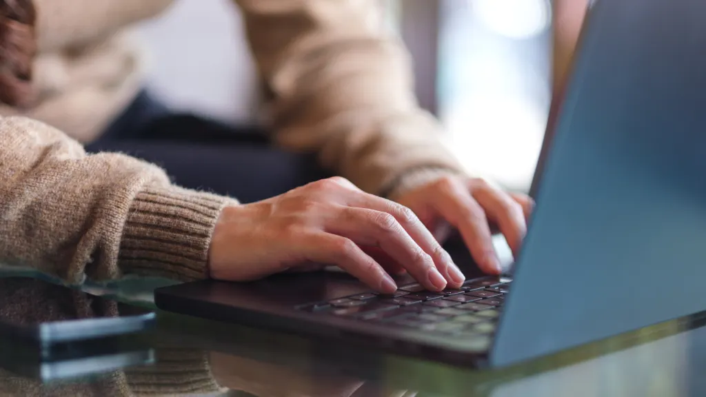 Close-up of hands typing on the keyboard of a black laptop