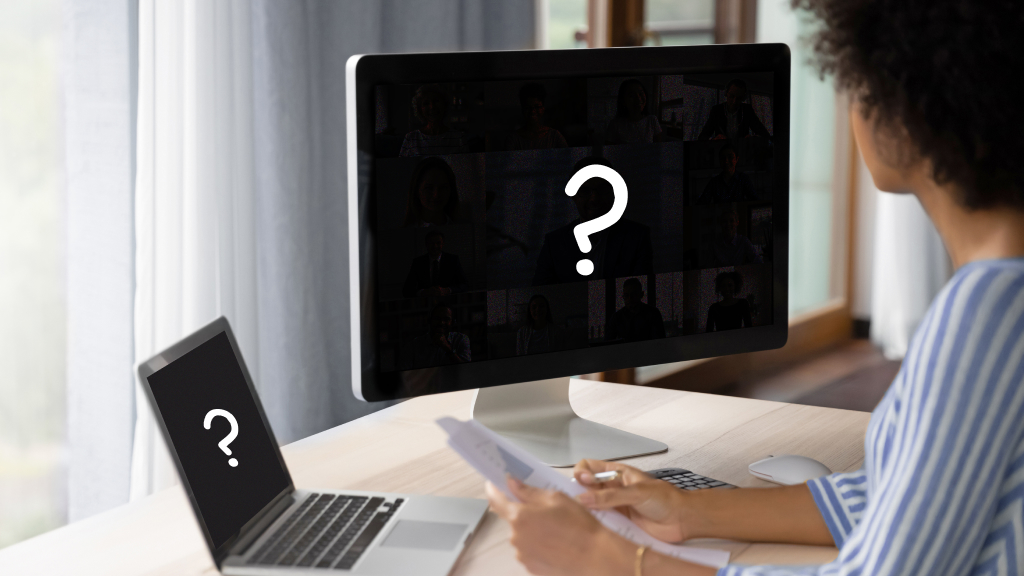 Person sitting at desk with Mac laptop and computer