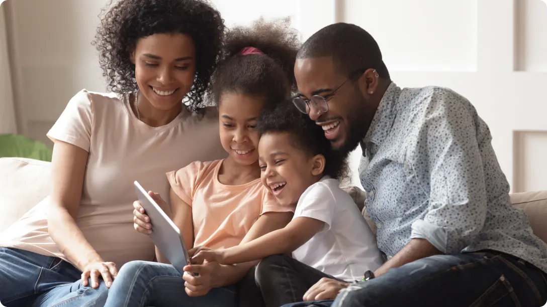 Family sitting together on a couch and using a tablet device