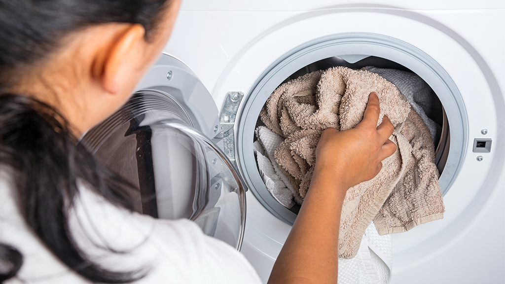 Woman loading laundry into smelly front load washer