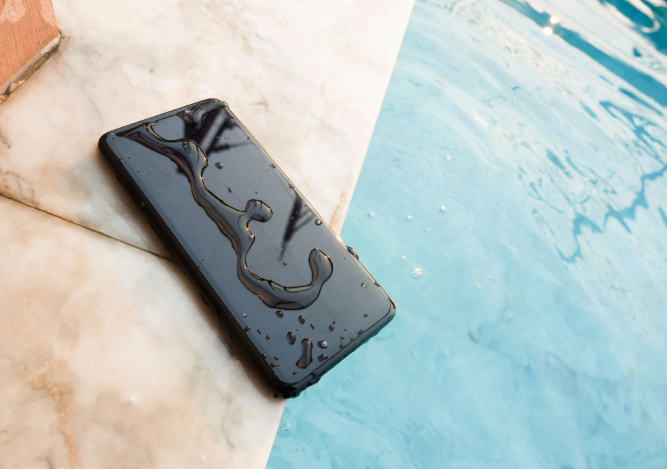 A wet phone sitting by a swimming pool