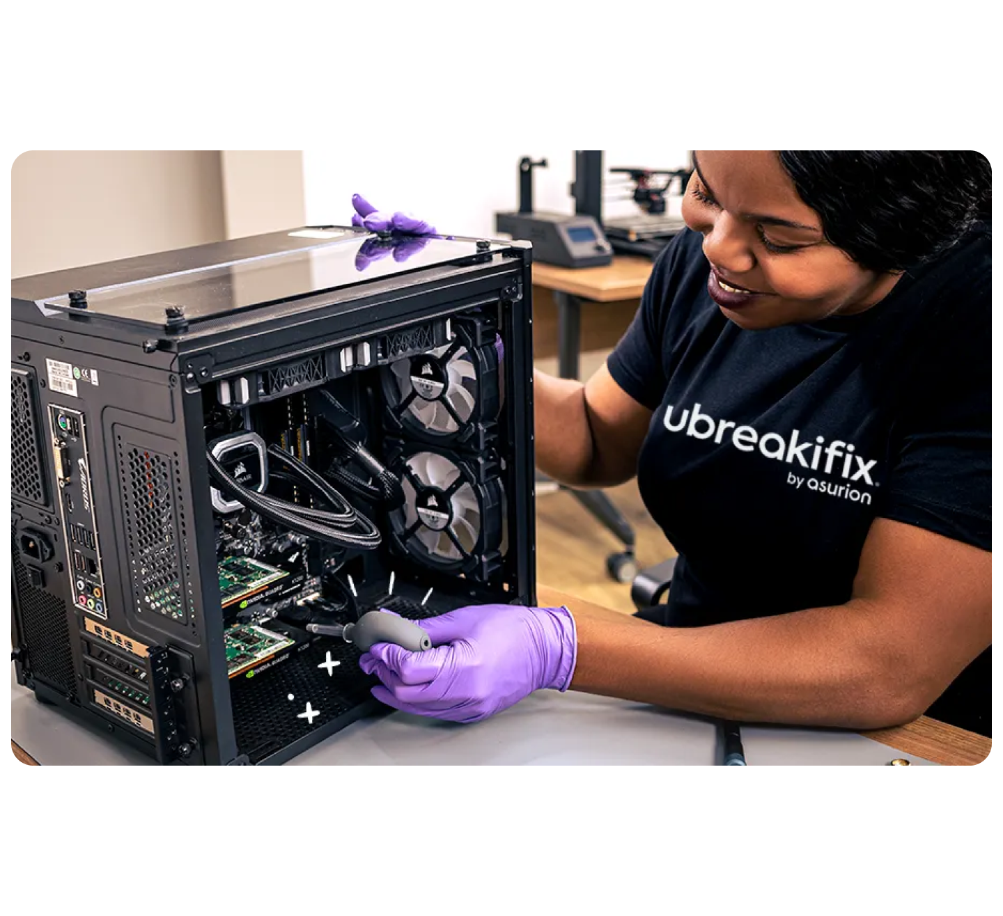 Technician wearing purple gloves repairing a desktop computer tower at a workbench