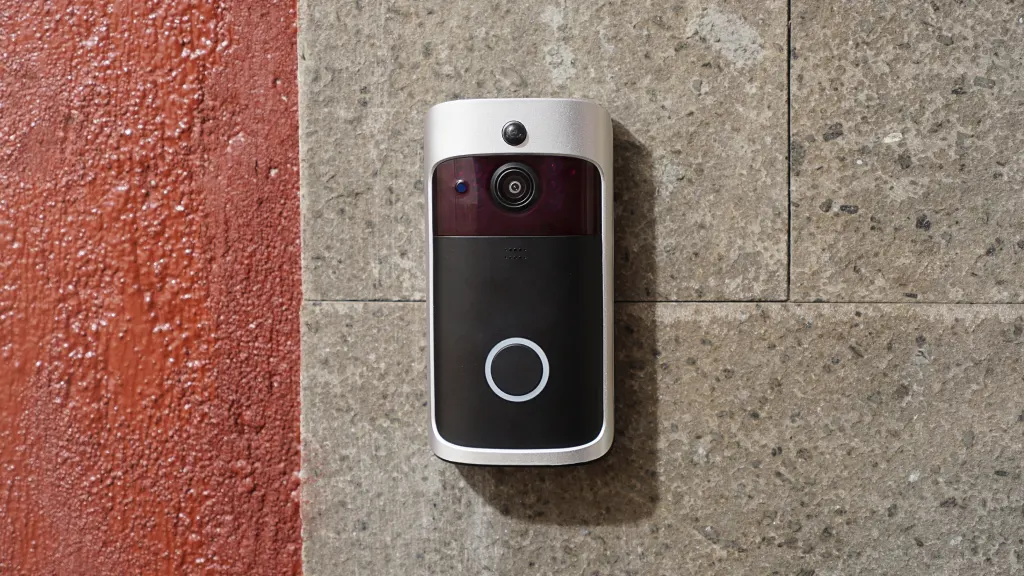 A wired doorbell with a camera mounted on a grey stone wall